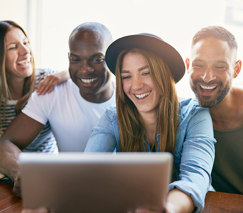 Diverse group smiling and collaborating on laptop, illustrating Movegistics 5.0’s supportive onboarding and team success.